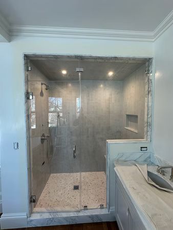 Modern bathroom with glass-enclosed shower, marble tile, and double vanity sink