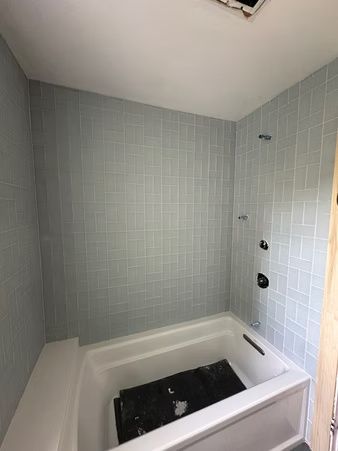 Small tiled bathroom with a white walk-in tub and gray walls