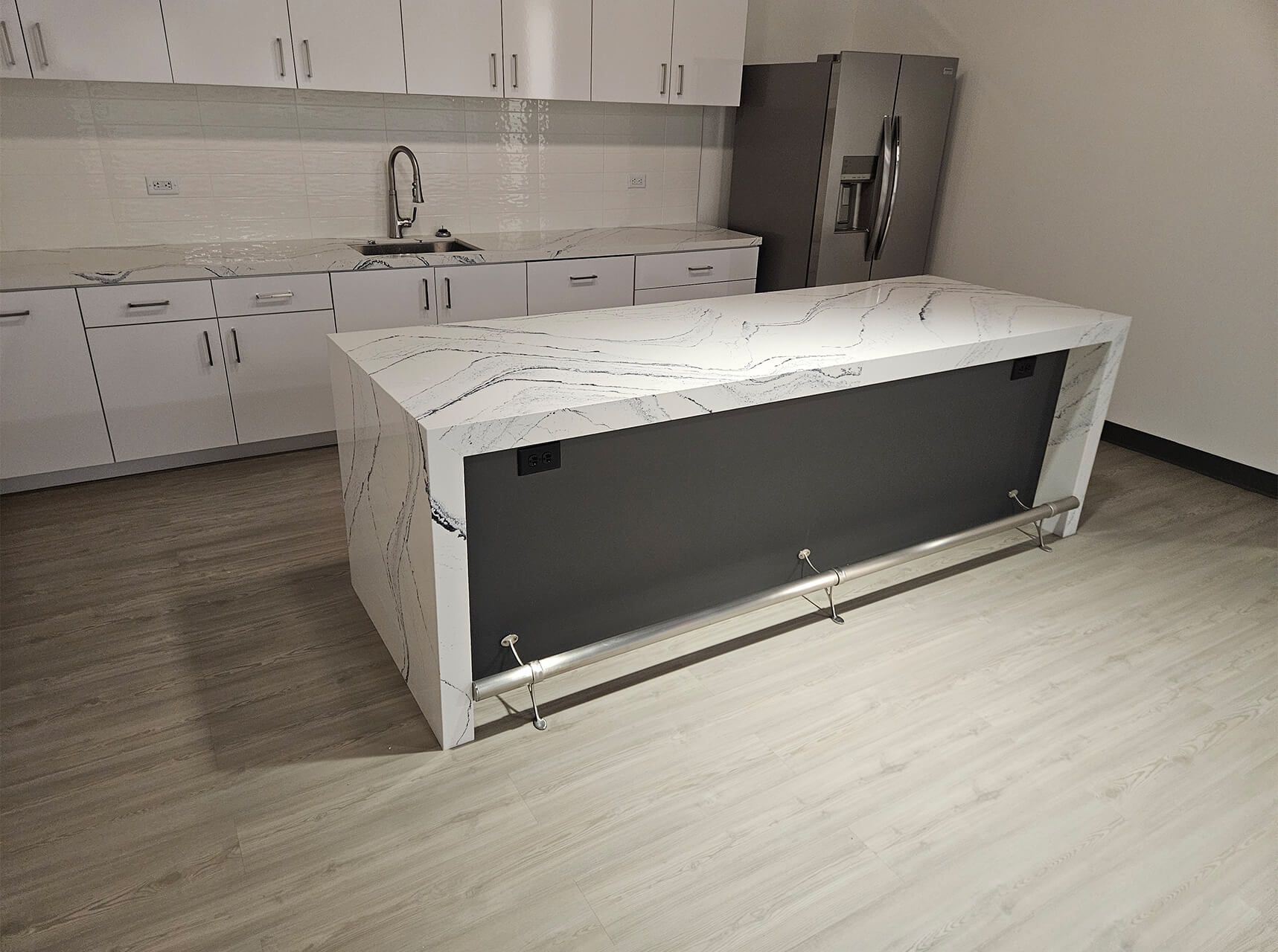 Modern kitchen with white cabinets and a large island, one cabinet panel open in the foreground