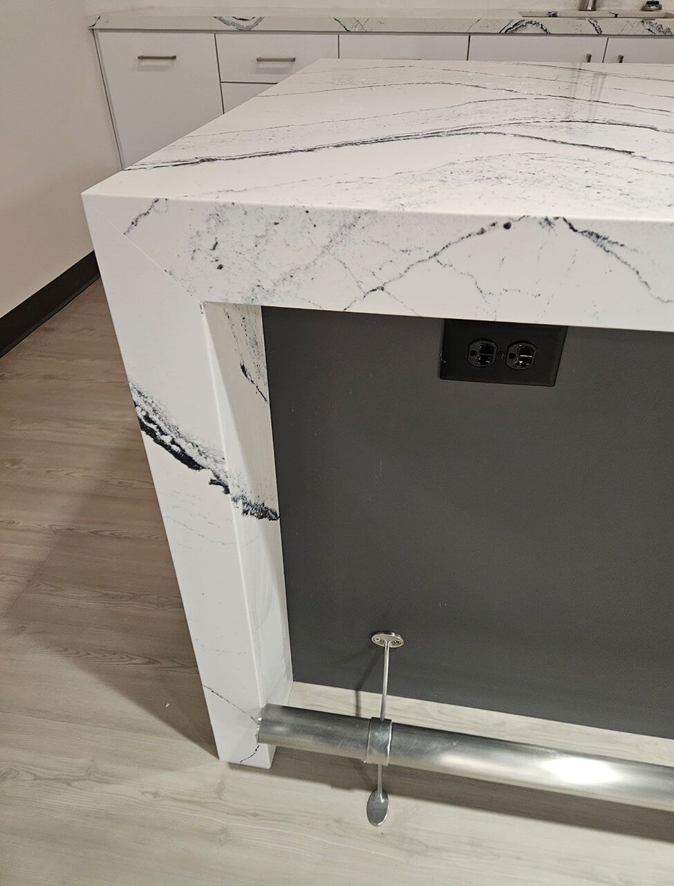 Modern white marble countertop with a dark cabinet opening underneath and a visible outlet