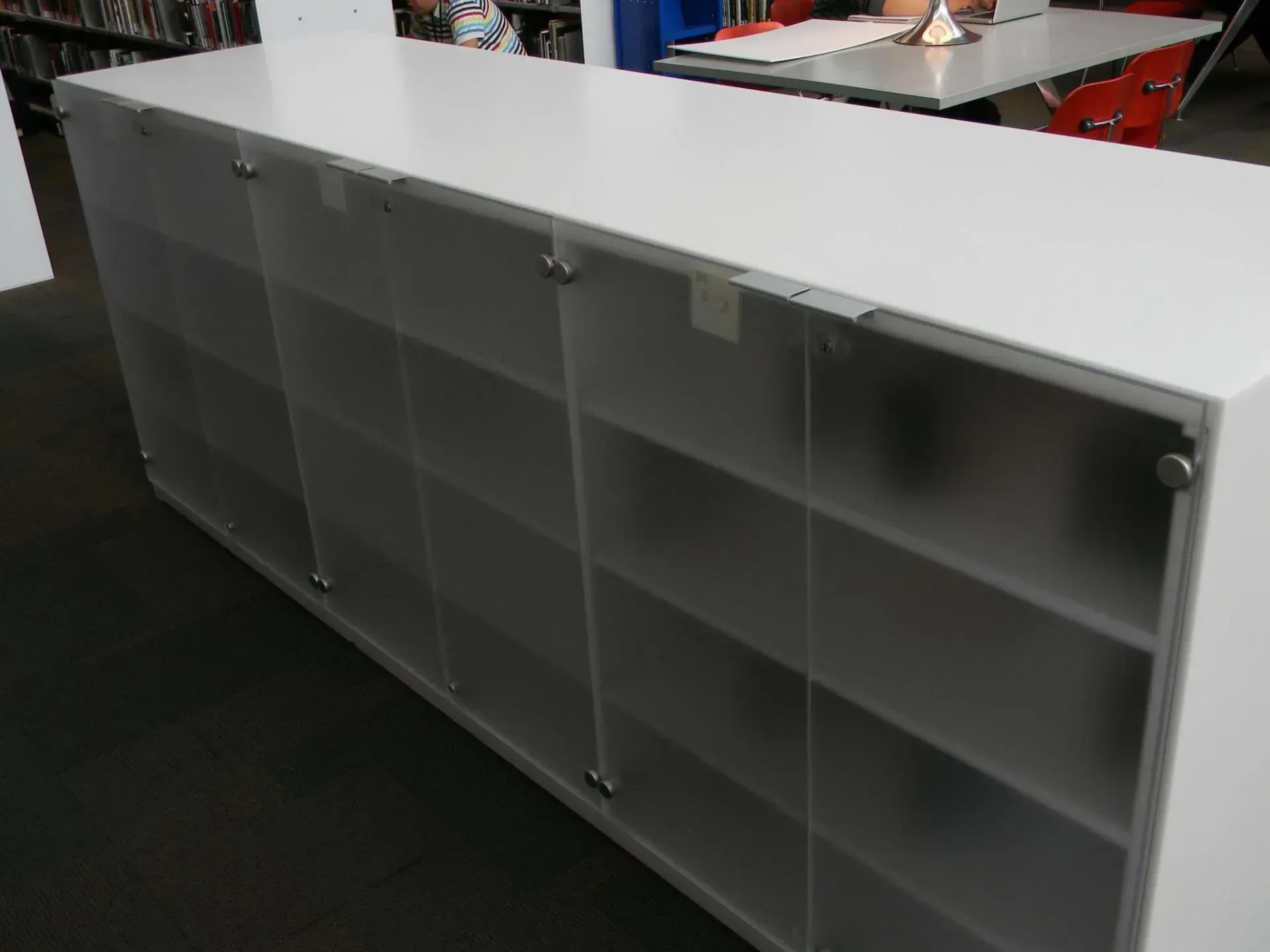 White locker-style storage unit with clear acrylic shelves in a room