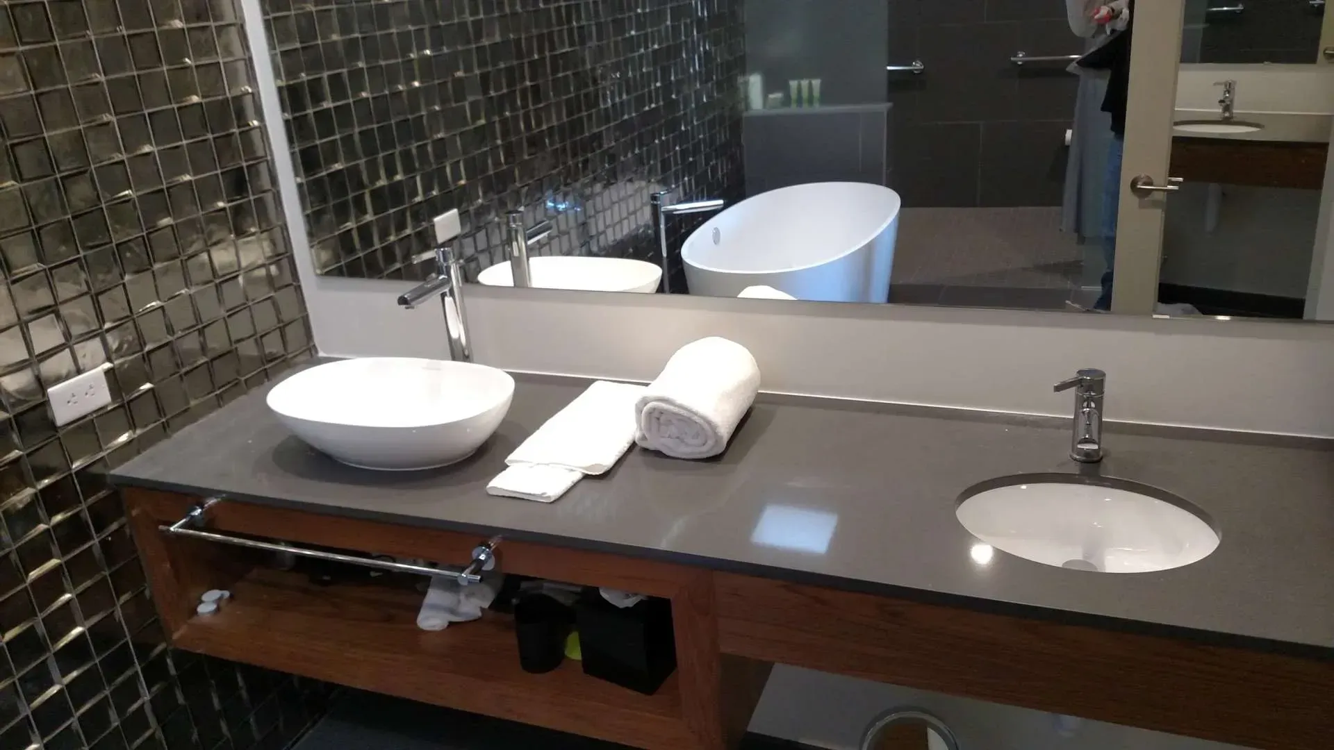Modern bathroom vanity with double sink, mirror, towel, and tiled wall
