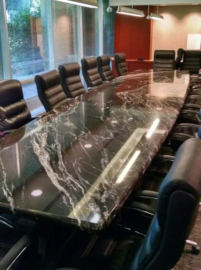 Conference room with a long glossy marble table and black leather chairs by large windows.
