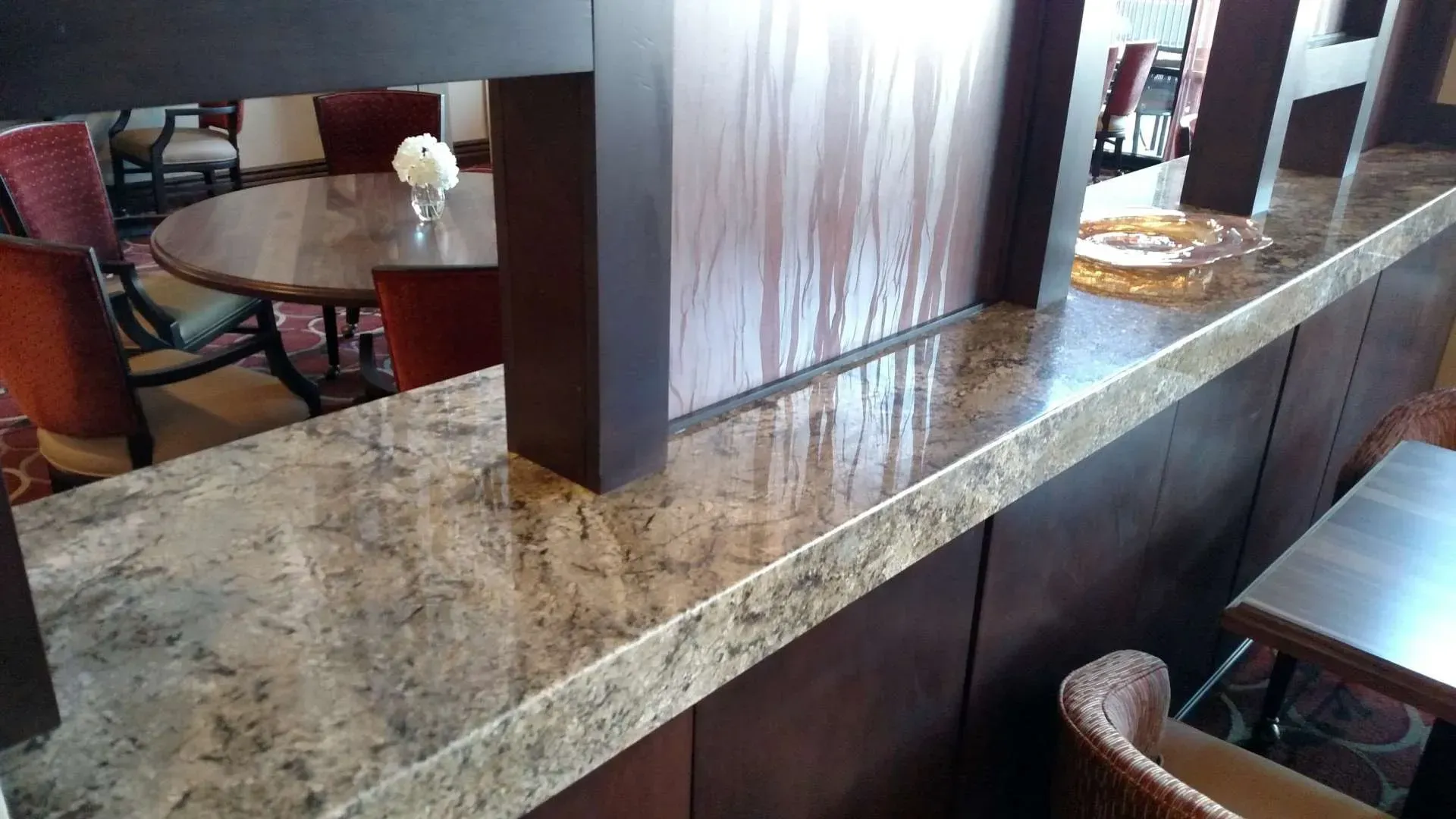 Marble countertop and wood divider in a restaurant seating area, with tables and chairs in the background