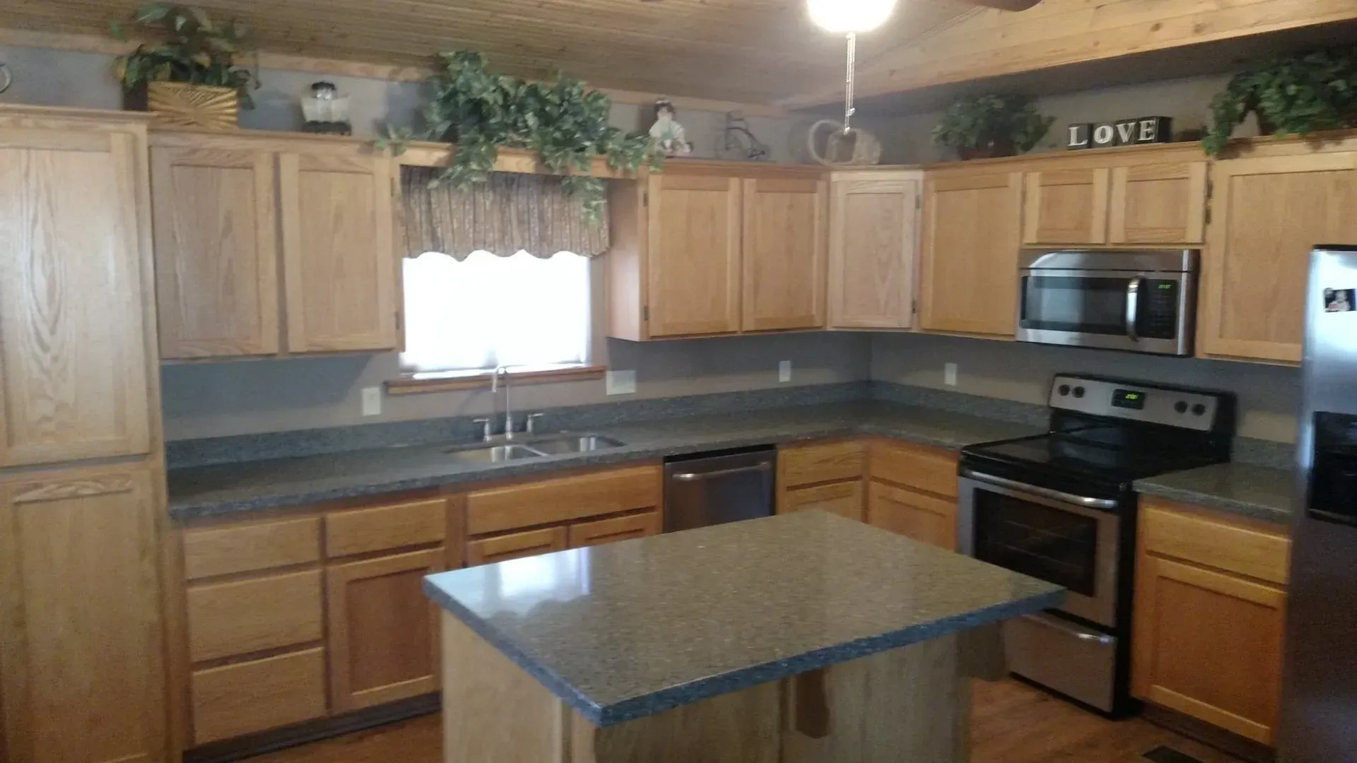 Spacious kitchen with wood cabinets, granite island, stainless appliances, and a window over the sink.