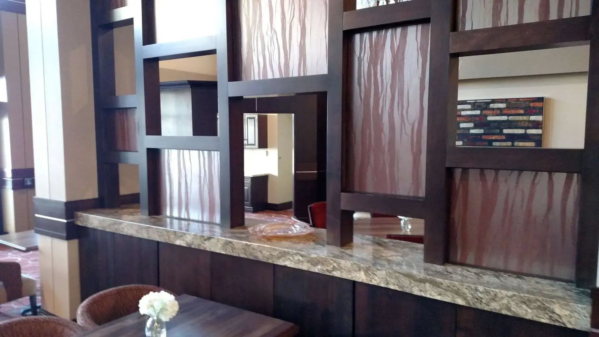 Wooden room divider with square cutouts and granite shelf in a modern lobby or lounge