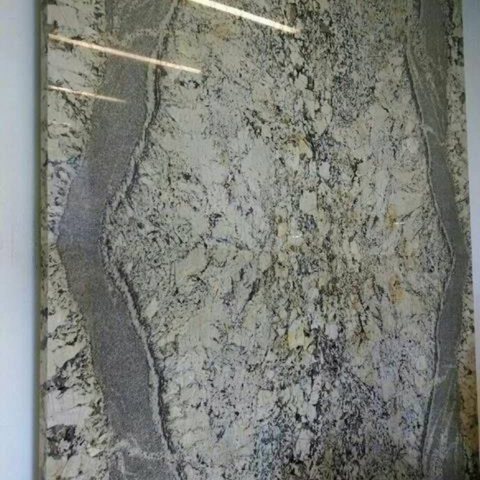 Gray and white speckled stone slab with veined patterns and reflections of overhead lights
