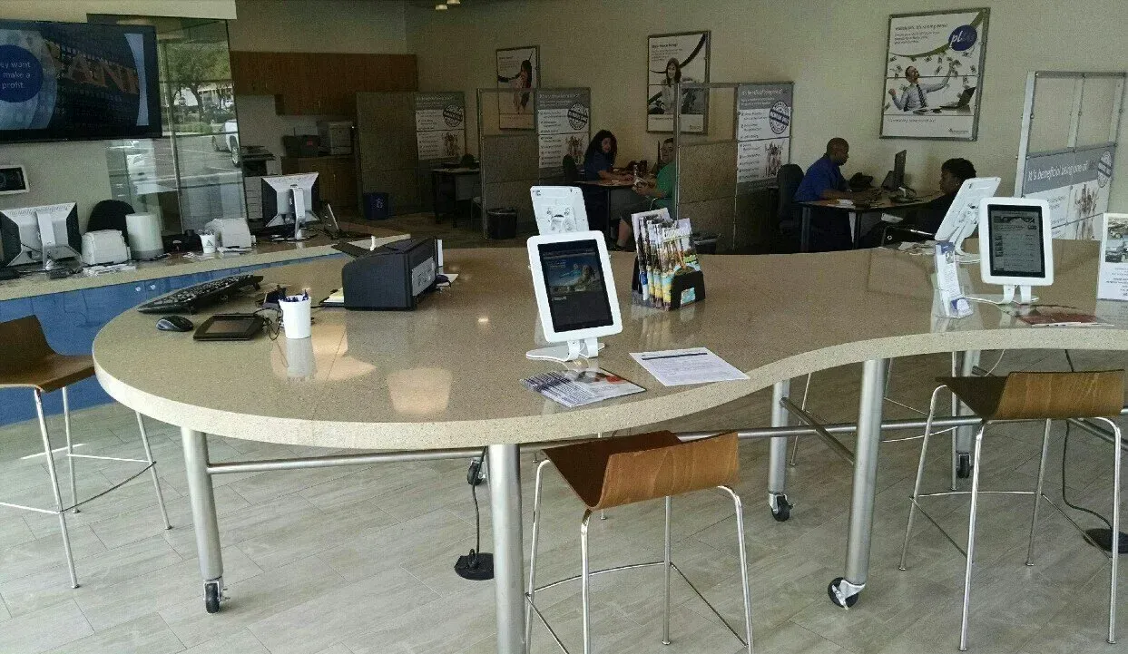 Quiet library or computer lab with a long round table, stools, and several desktop computers.