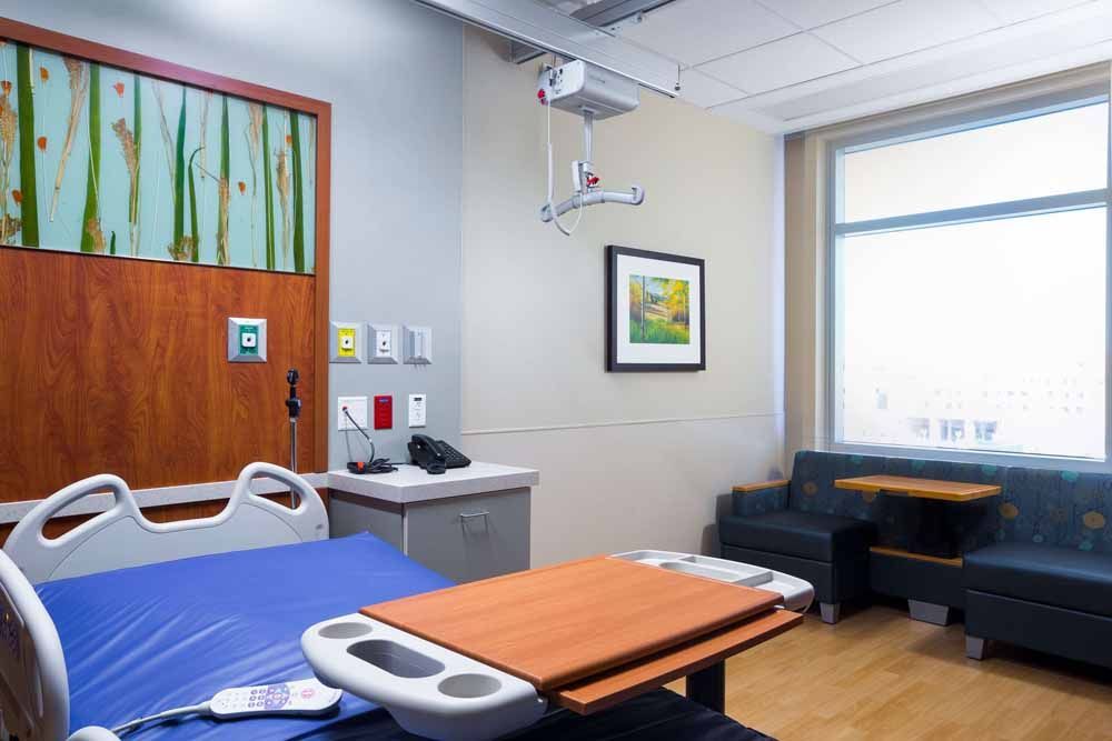 a hospital room with a bed , table , chairs and a window