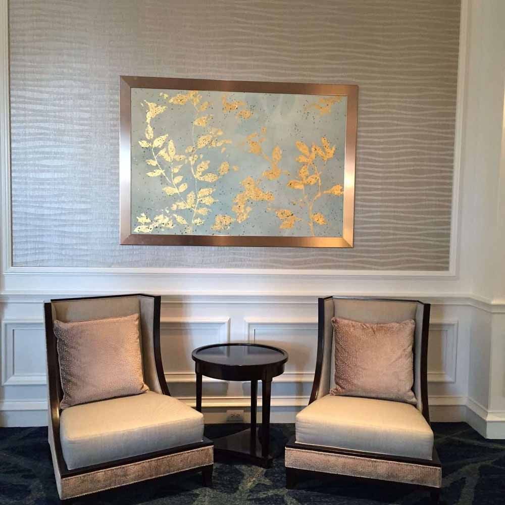 two chairs and a table in a room with a picture on the wall above them