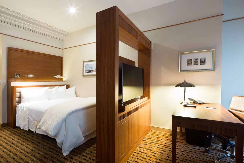 a hotel room with a bed , desk and television