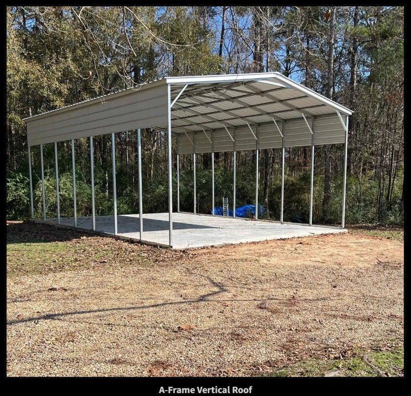 A-frame metal carport with vertical roof on a concrete pad, in a wooded area.