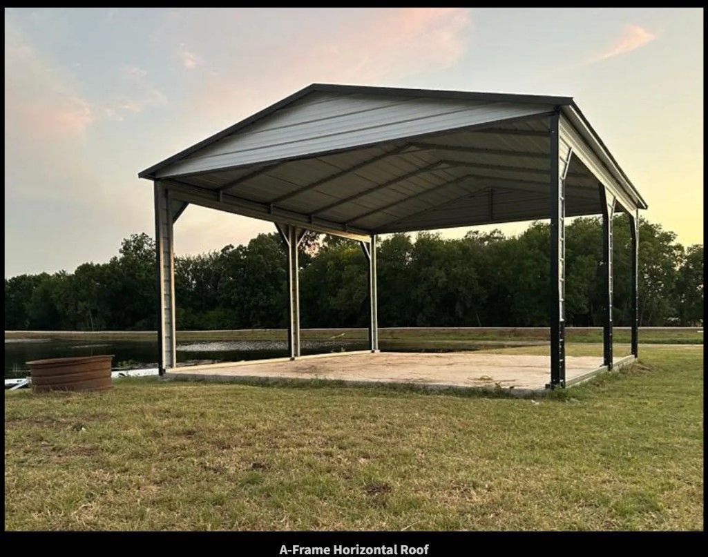 Metal carport on a concrete slab, set in a grassy field near a body of water, against a dusky sky.