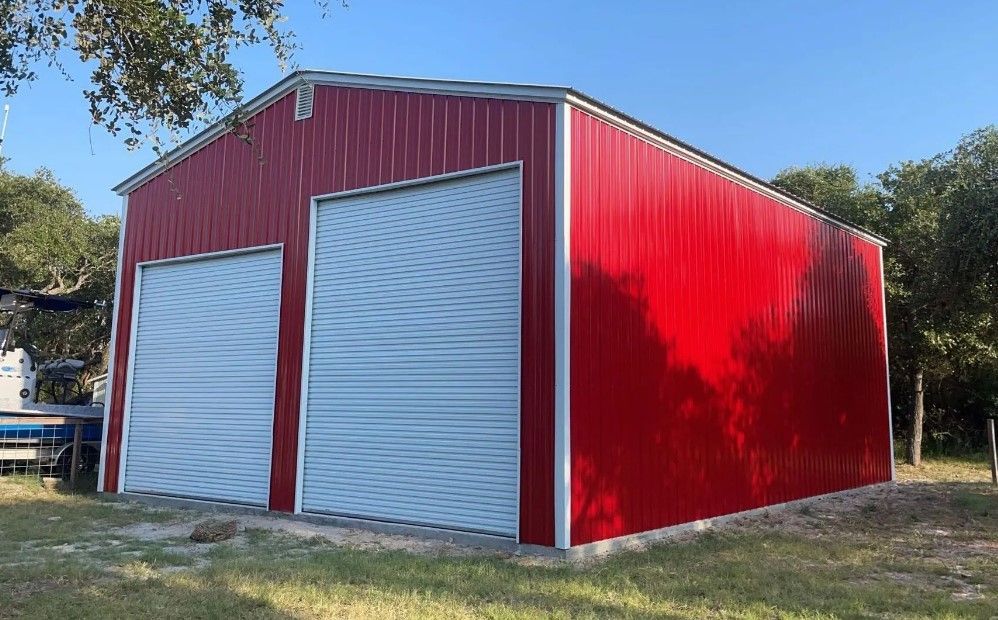 A red barn with white doors and a boat in the background