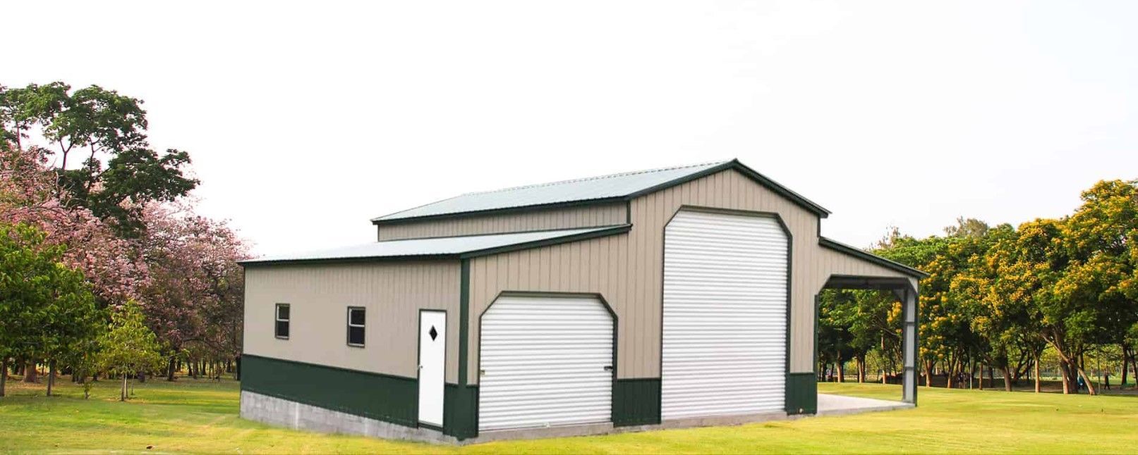 A large metal building with two garage doors is sitting in the middle of a grassy field