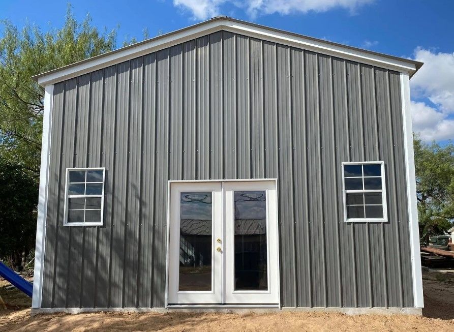 A large gray metal building with white trim and windows