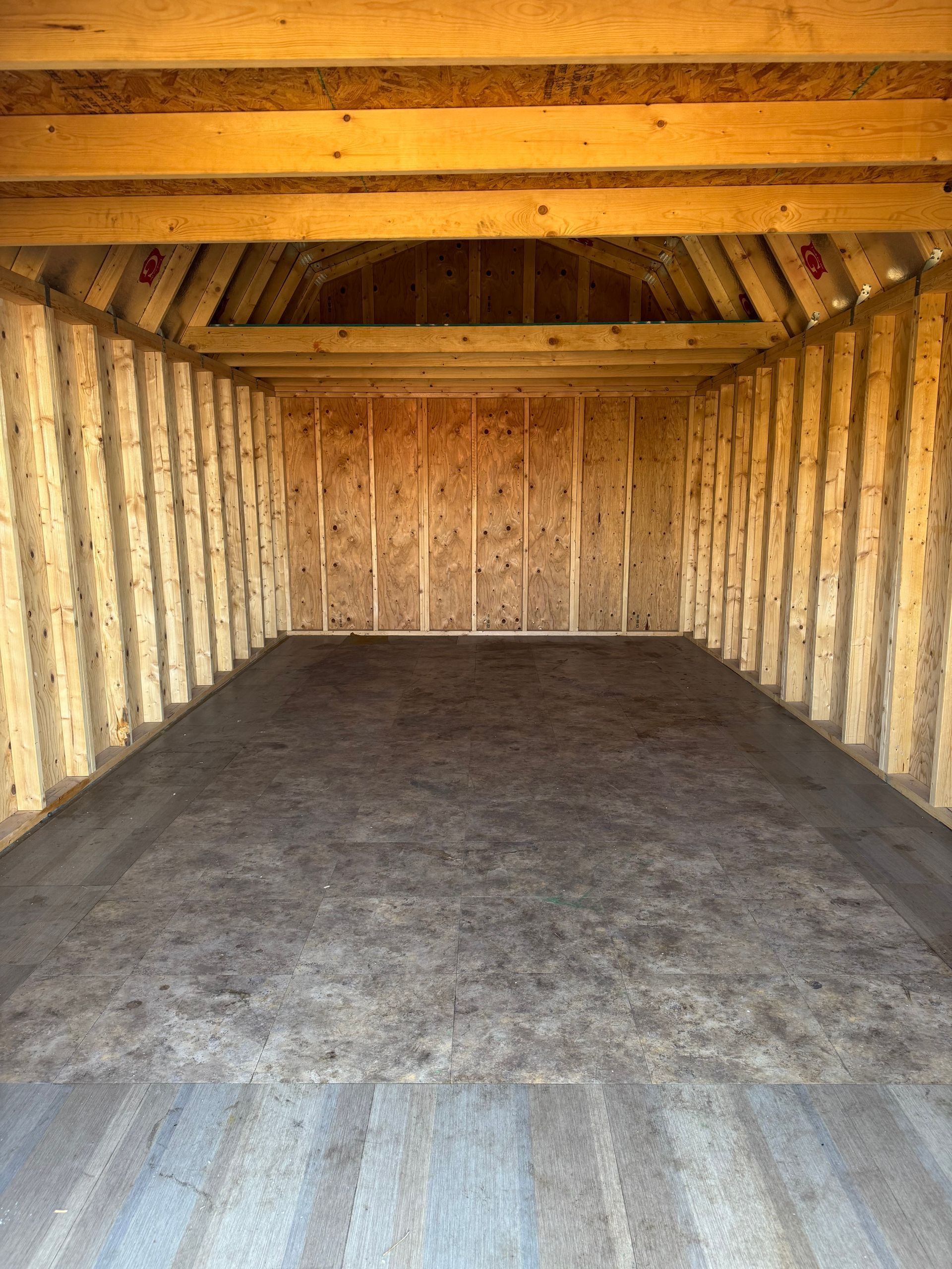 Interior of a wooden shed with plywood walls and floor, empty.