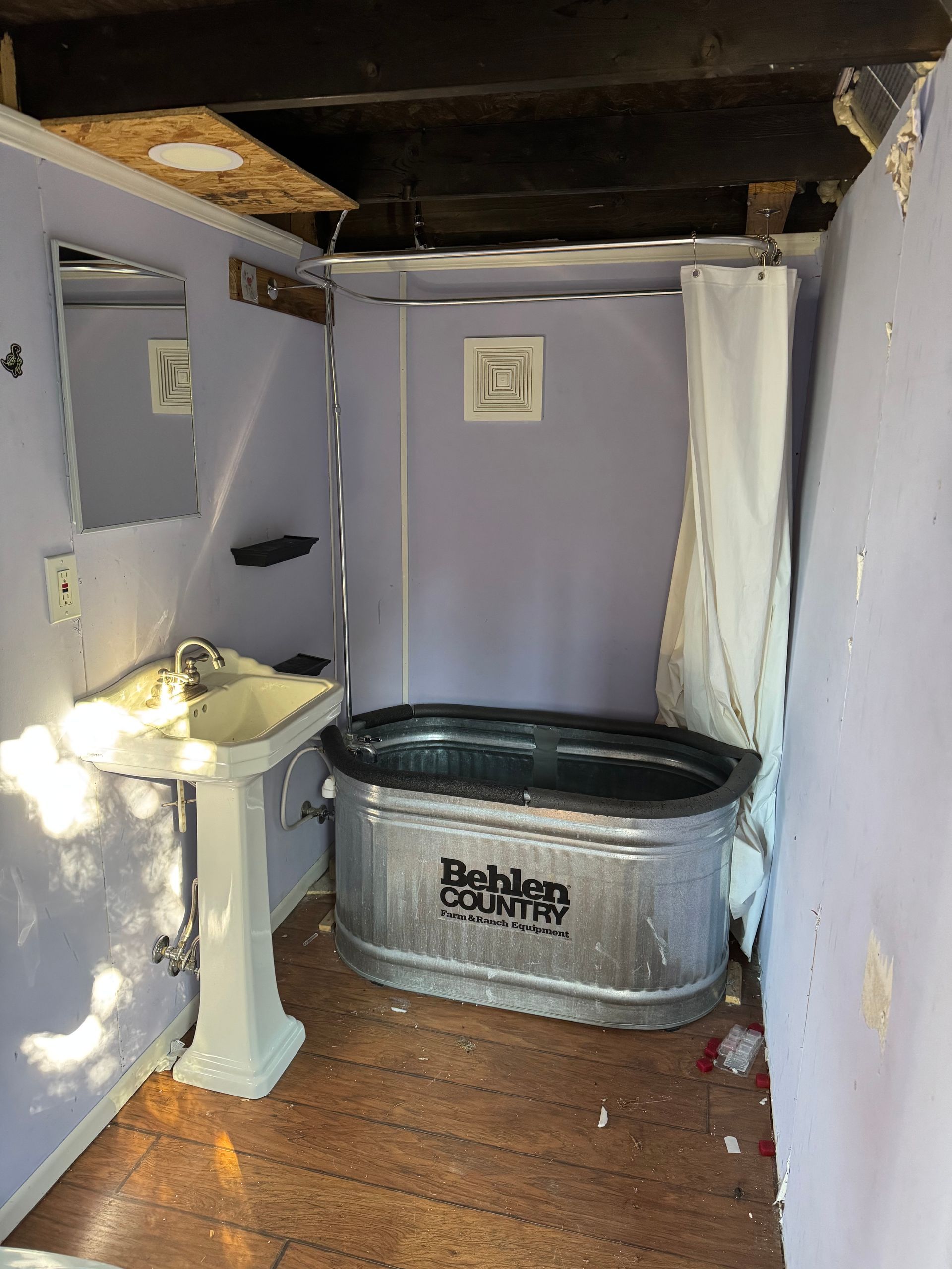 Dilapidated bathroom with a galvanized metal tub, sink, and shower curtain.