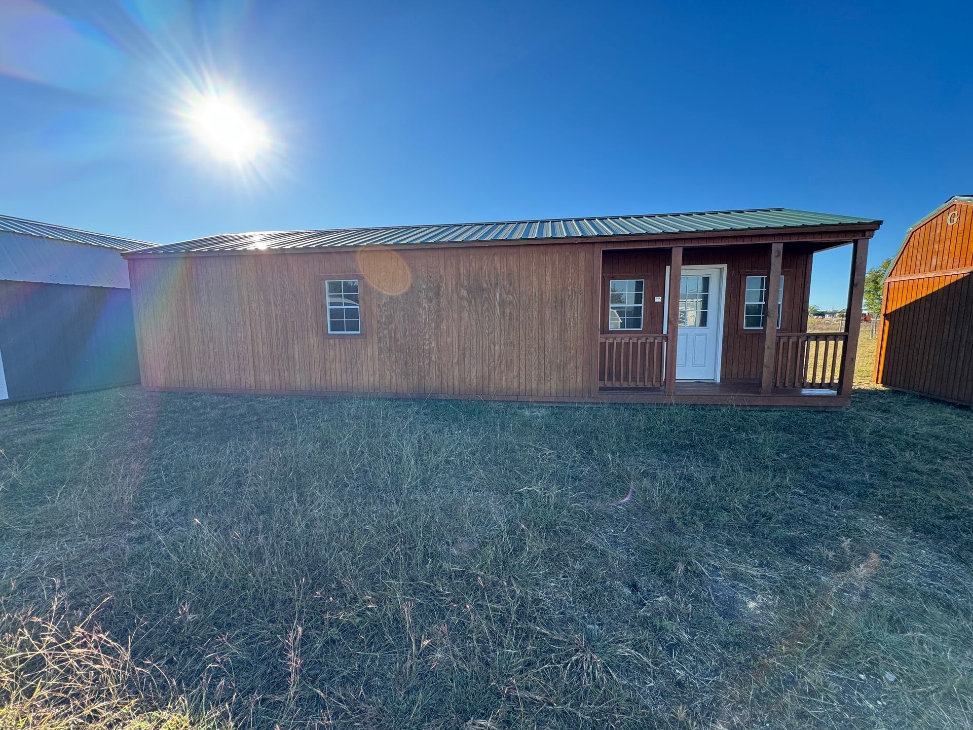 Cabin with wooden exterior and small porch under a sunny sky.