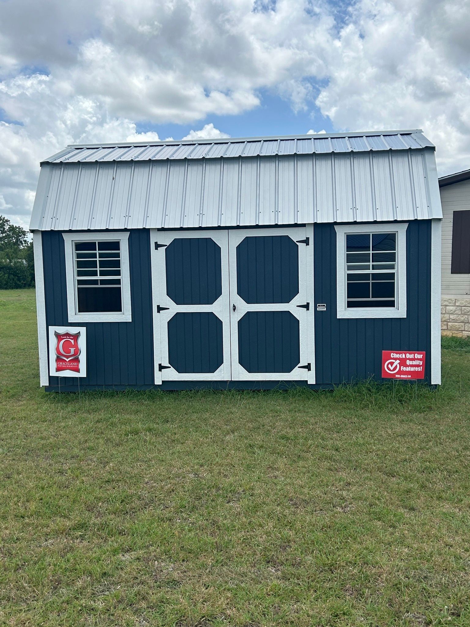 A blue and white barn is sitting in the middle of a grassy field