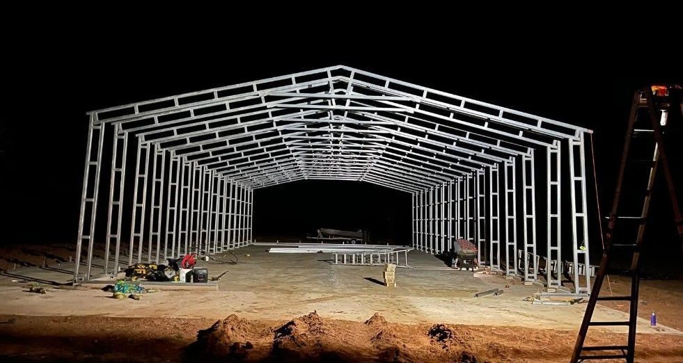 Steel frame building under construction at night.