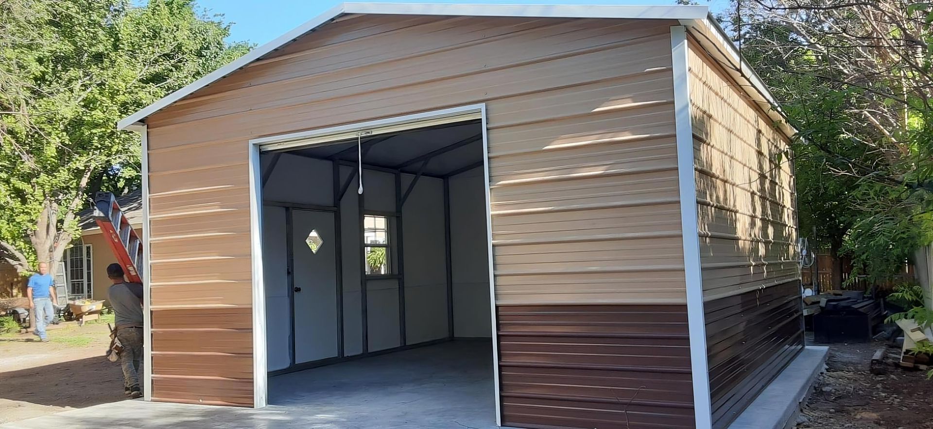 Metal garage with open door, brown siding, and white trim against a tree-lined background.