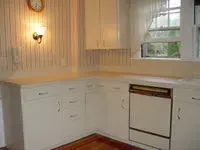 Bright white kitchen with cabinets, sink, wall sconce, and window over the counter.