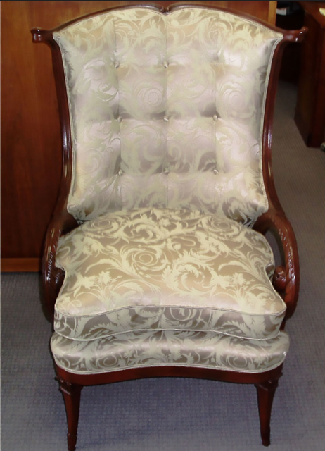Antique upholstered armchair with floral fabric and dark wooden frame on a carpeted floor