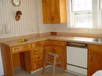 Small kitchen with wooden cabinets, white appliances, and a window over the sink.