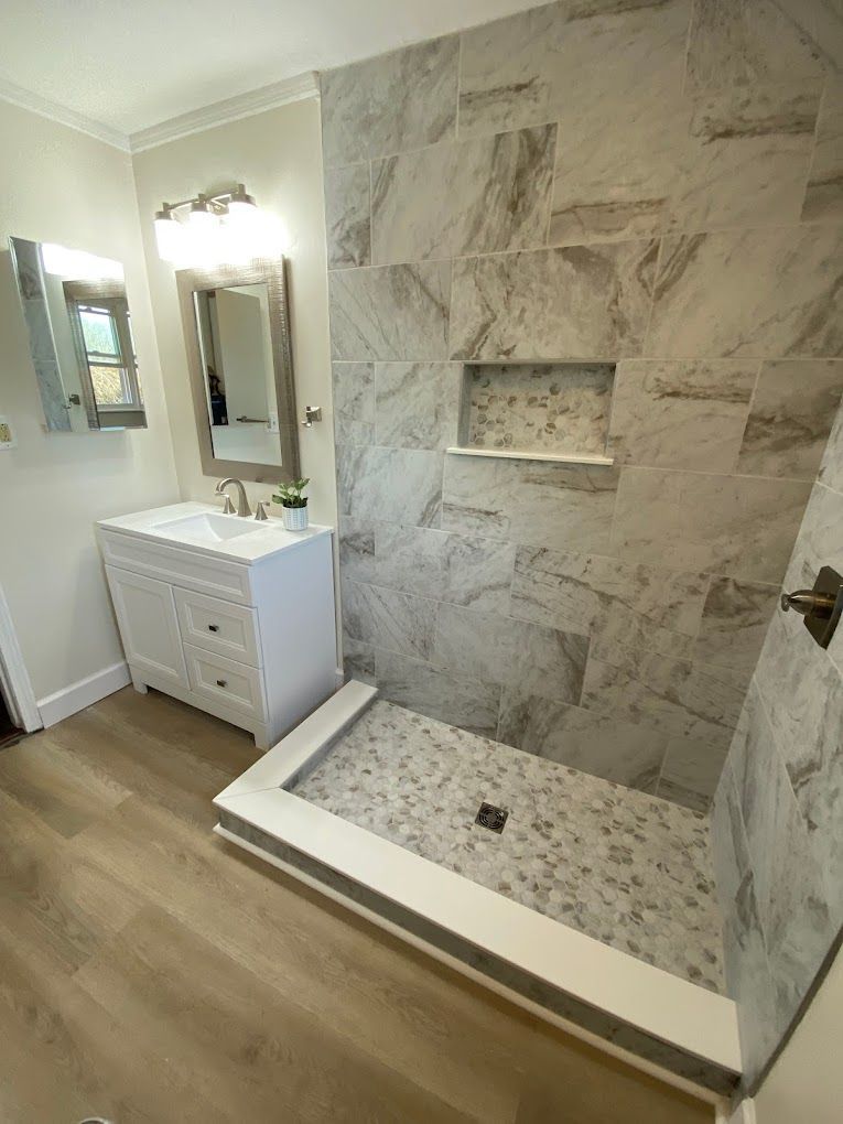A bathroom with a walk in shower, sink and mirror.