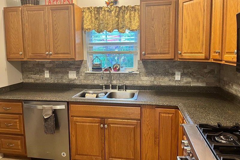 A kitchen with wooden cabinets, granite counter tops, stainless steel appliances and a sink.