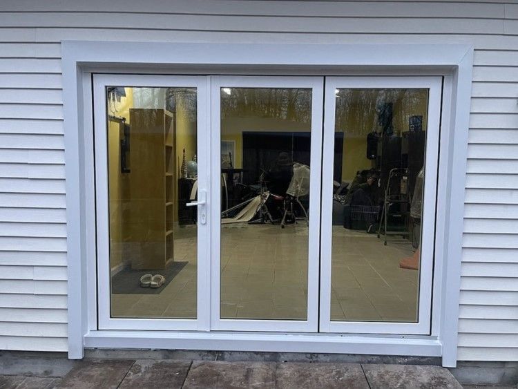 White framed glass doors set in white siding, reflecting interior items.