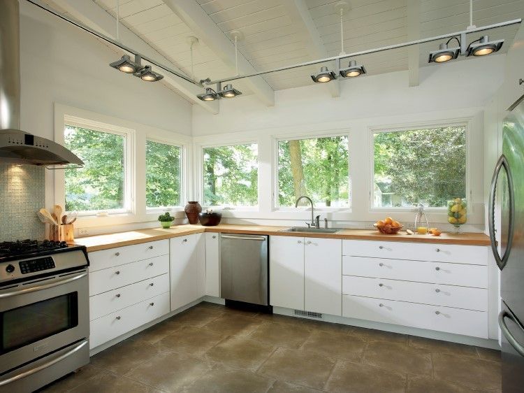 Bright, white kitchen with windows overlooking greenery, white cabinets, and stainless steel appliances.