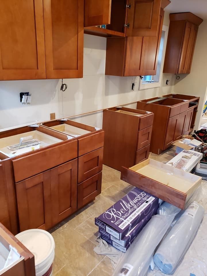 Kitchen cabinets in various stages of installation; warm brown wood, unfinished walls.