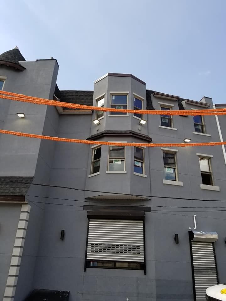 Gray building with multiple windows, a cylindrical turret, and a roll-up door.