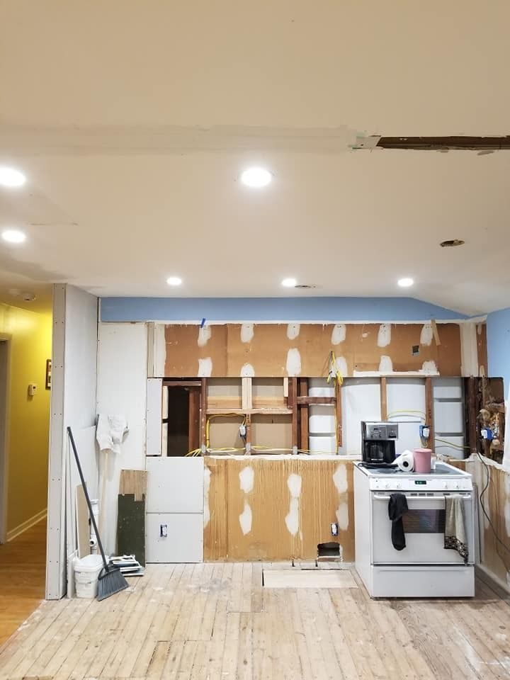 Kitchen undergoing renovation: exposed studs, appliances, demolition debris.