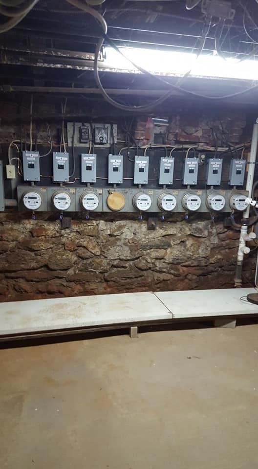 Row of electric meters mounted on a stone wall.