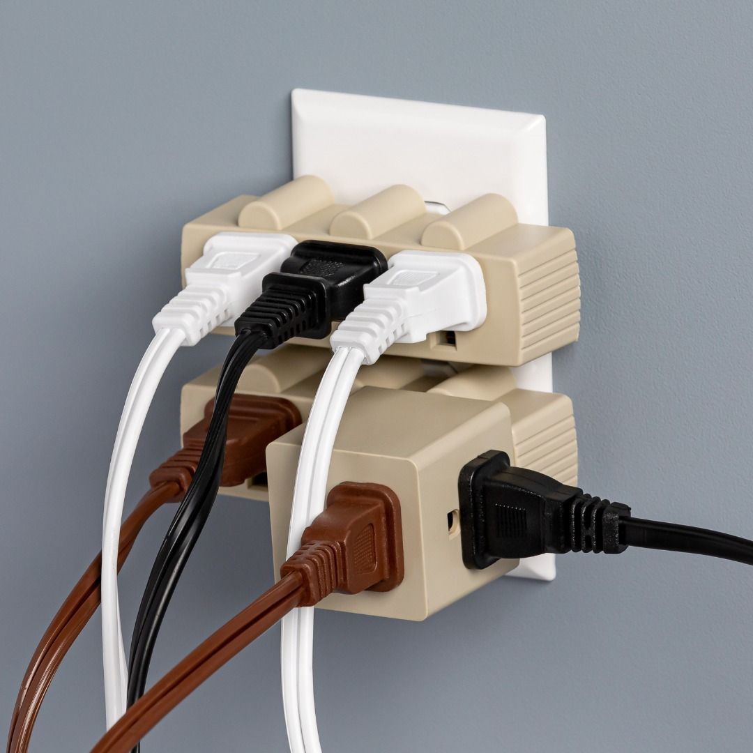 Stacked power outlet adapters with several cords plugged into them.