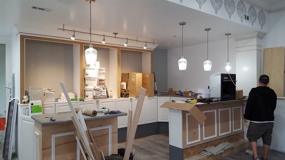 Interior under construction, with lights, cabinets, and a person observing.