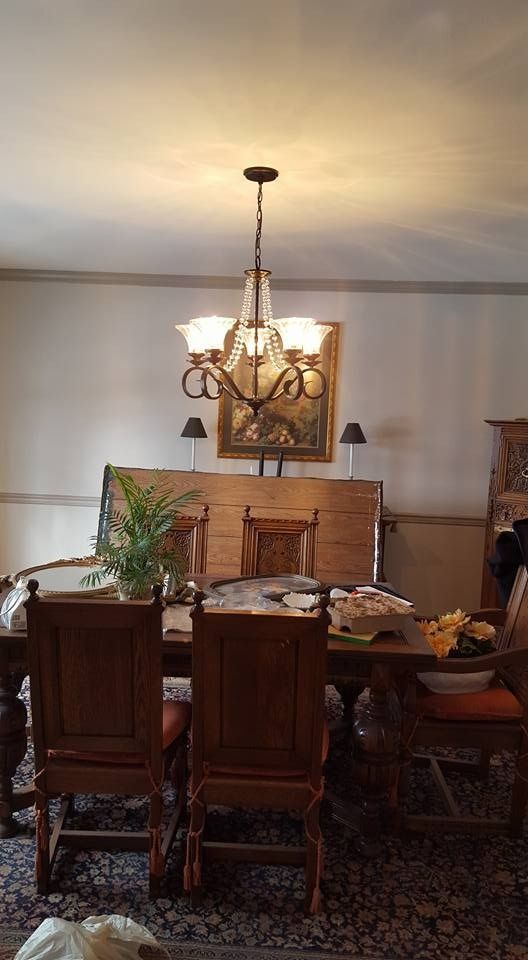 Dining room with chandelier, wooden table and chairs, and a rug.
