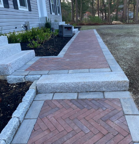 Brick pathway with granite steps leading to a house entrance.