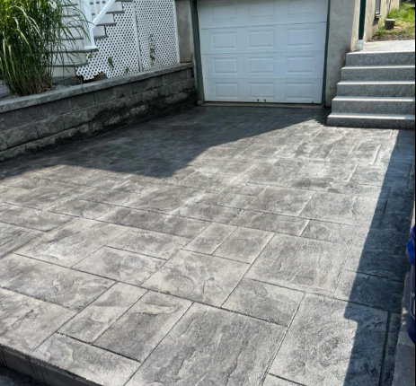 Stamped concrete driveway in gray tones with garage and steps.