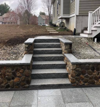 Stone steps with stone and rock retaining walls leading up to a house.