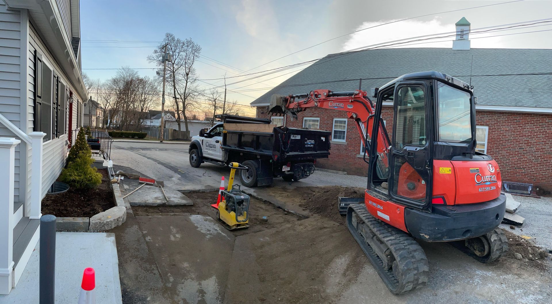 Construction site with excavator and dump truck on a street. Workers removing asphalt and preparing for a new surface.