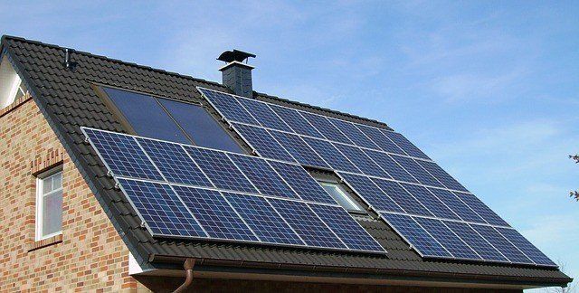 House roof covered with blue solar panels under a clear sky