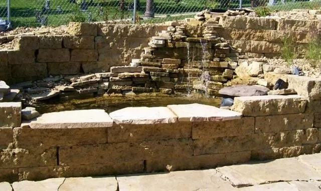 Stone ruin with a shallow circular pool and stepped stone seating in a sunny outdoor setting