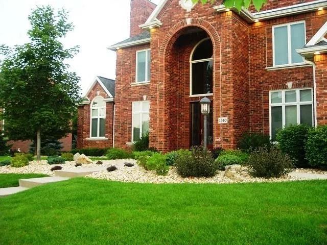 Brick building with arched entrance, white windows, and green lawn in front