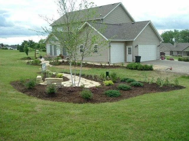 Suburban house with landscaped flower bed and young tree in front yard