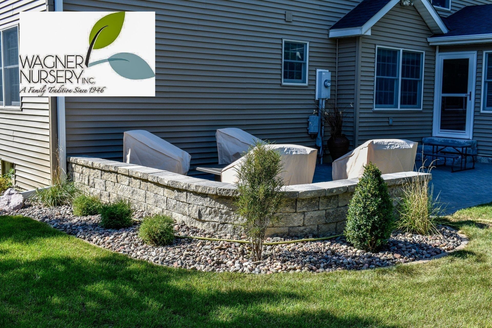 Backyard stone patio with outdoor seating, gravel border, and lawn beside a house