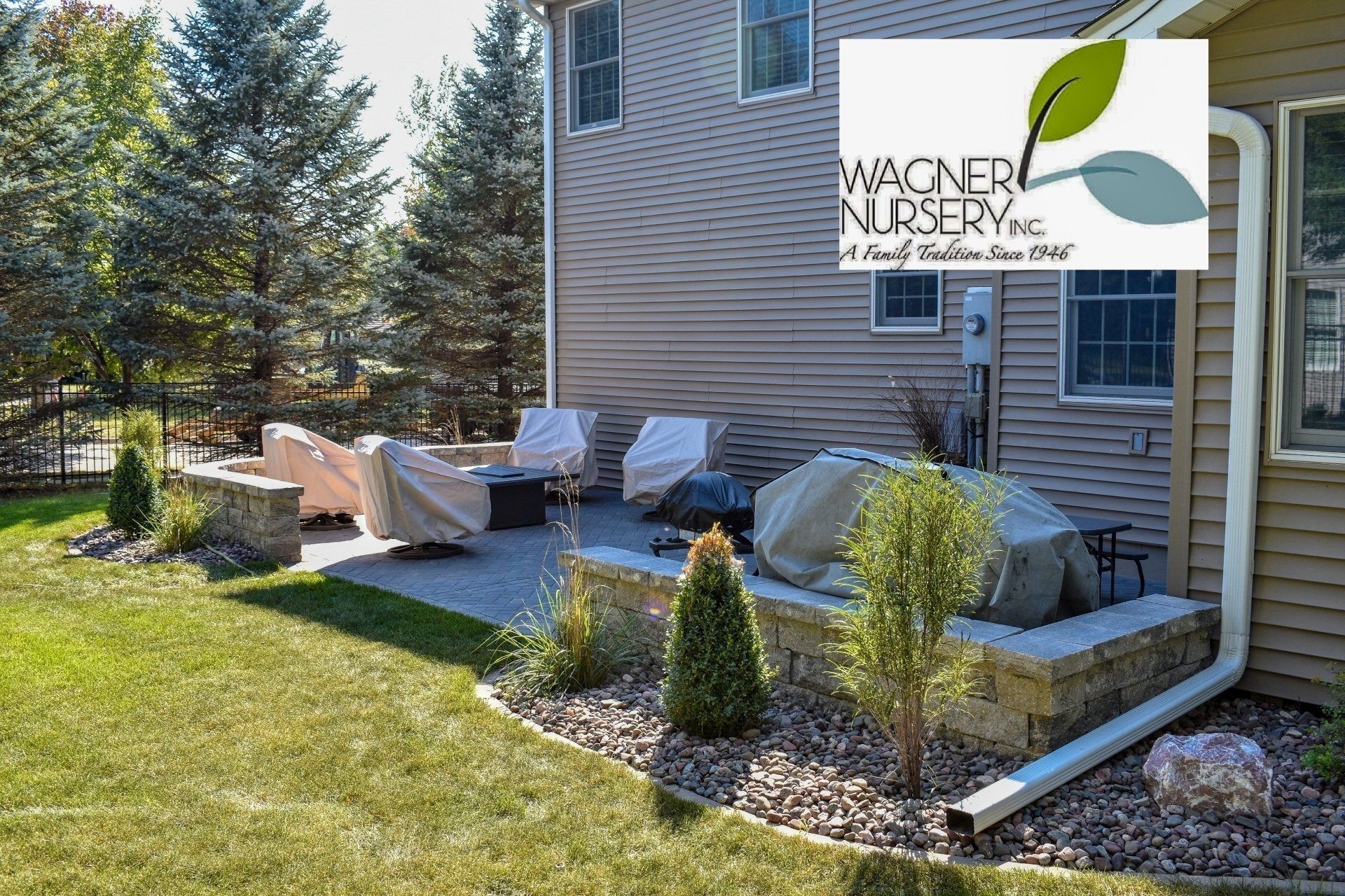 Backyard patio with lounge chairs, covered grill, and Water Nursery logo on house wall